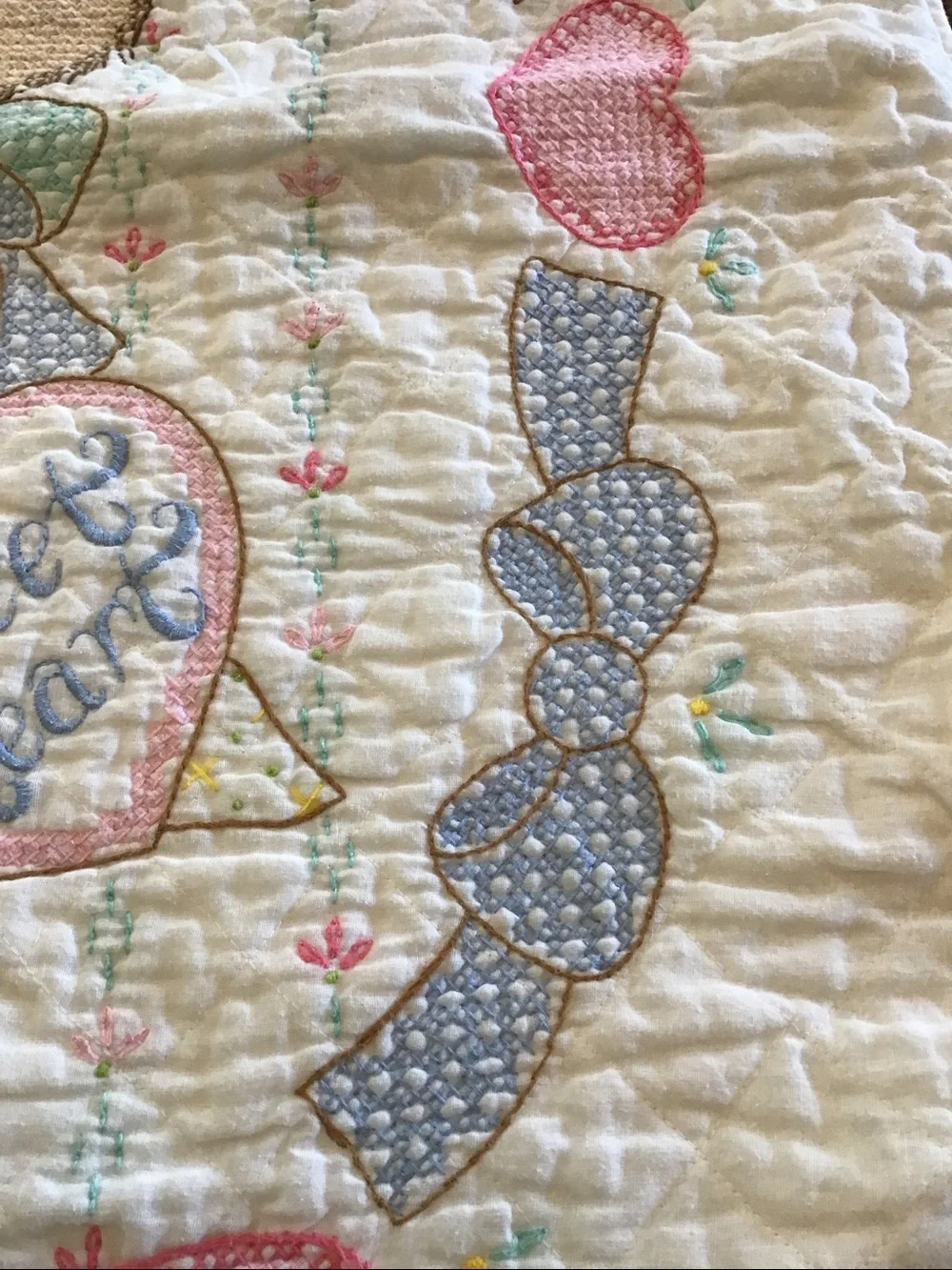 Vintage handmade baby quilt featuring embroidered teddy bears
